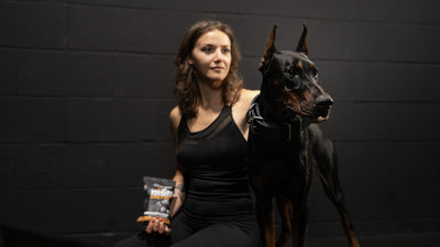 Woman sitting with her Doberman and holding a bag of Bully Max dog food: is lamb good for dogs